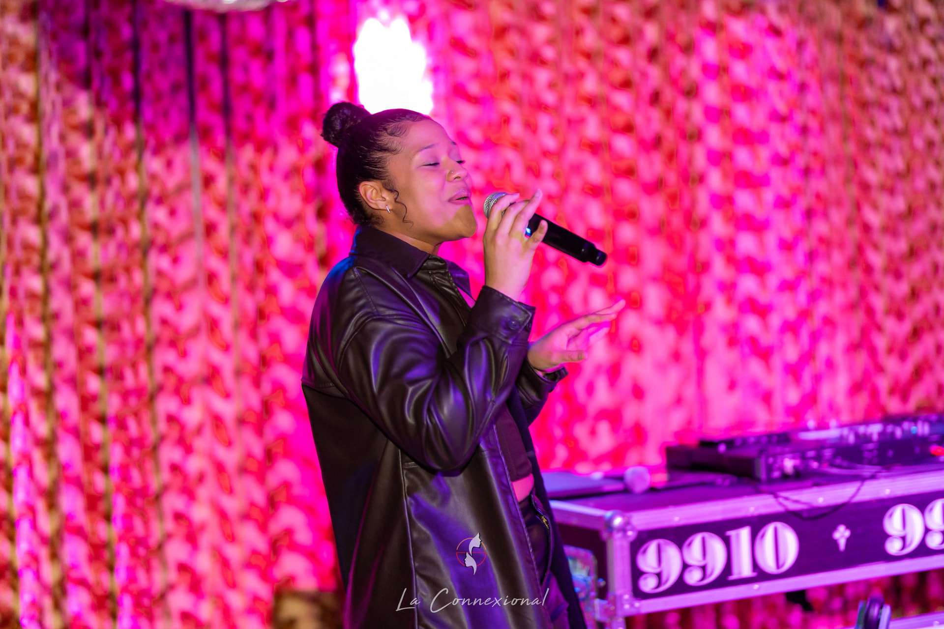 Ezeada singing in profile under vivid pink lights