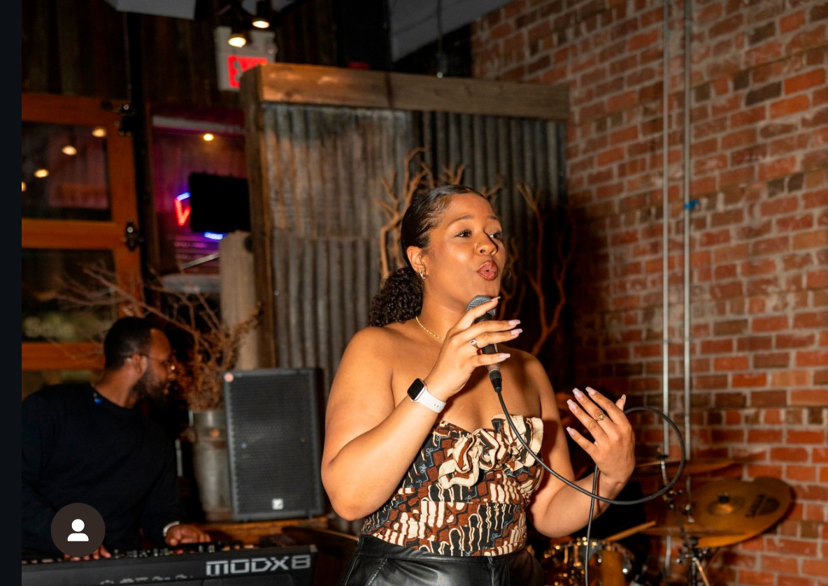 Ezeada performing with a live keyboard player in a brick-walled venue